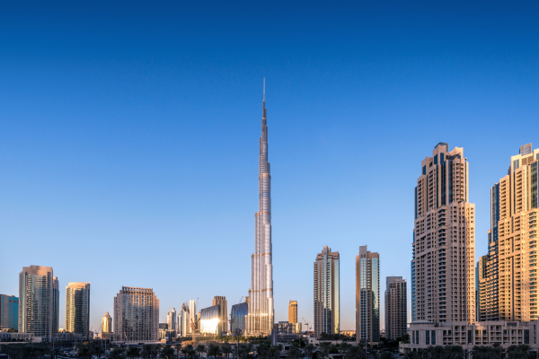 Dubai skyline at sunset with the Burj Khalifa towering above modern high-rise buildings under a clear blue sky