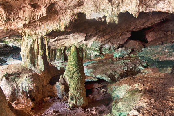 Limestone cave interior with rugged stalactites, stalagmites and textured rock formations illuminated by natural light