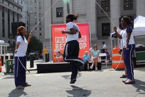 A person jumps between two ropes during a double dutch activity on a city street