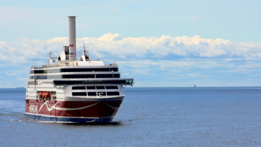 Passenger ferry sailing across calm blue ocean under a partly cloudy sky