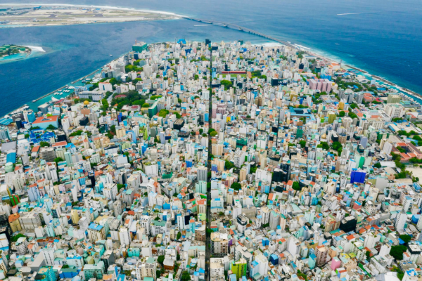 Dense urban skyline of Malé in the Maldives seen from above with high-rise buildings, bridge, harbor and turquoise coastline