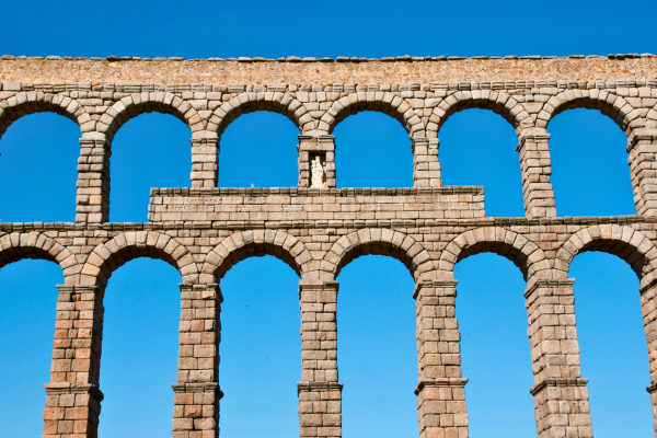 Ancient Roman aqueduct with rows of stone arches against a clear blue sky