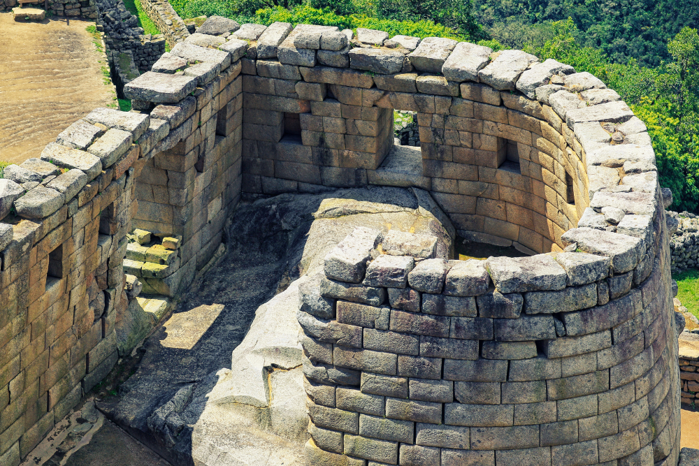 Curved stone structure with finely cut granite blocks, windows, and interior passageways at an ancient archaeological site