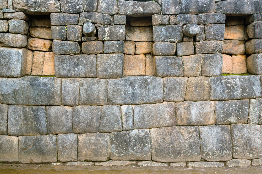 Close-up of a stone wall built from tightly fitted rectangular granite blocks with small trapezoidal niches carved into the upper section